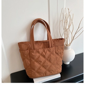 Detail of brown quilted tote bag showing rhombus stitching and large front pocket