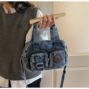 Detail of washed blue denim mini bag showing multi-pockets and leather logo patch