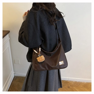 Detail of dark brown hobo bag with teddy charm, contrast stitching and fashion tag