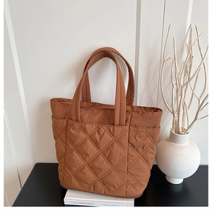 Detailed view of brown quilted tote bag showing large main compartment and side pockets