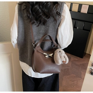 Detail of dark brown litchi pattern leather bucket bag with silver buckle and bunny charm