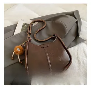 Dettaglio della borsa a secchiello in pelle cerata marrone con ciondolo mostriciattolo