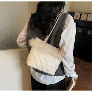 Detail of quilted crossbody bag featuring plush faux fur trim and gold chain strap