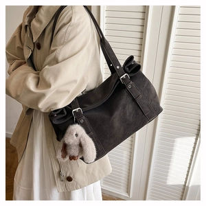 Detail of a large matte hobo bag with silver buckles and a cute bunny plush charm
