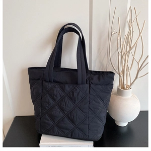 Close-up of black quilted tote bag with large diamond stitching and spacious front pocket