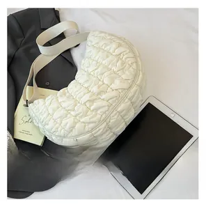 Détail de la texture plissée et de la large bandoulière du sac croissant blanc cassé