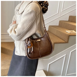 Braune Leder-Eimertasche mit Leoparden-Anhänger und Metallschnalle getragen von Model