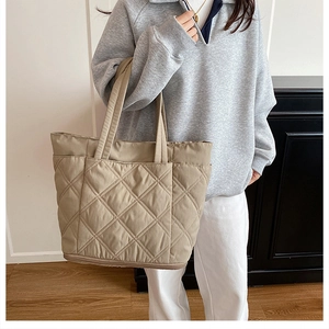 Detail of quilted tote bag featuring large diamond stitching and soft beige nylon texture