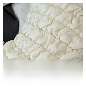 Vue détaillée du tissu matelassé blanc crème montrant les coutures fines et la texture douce