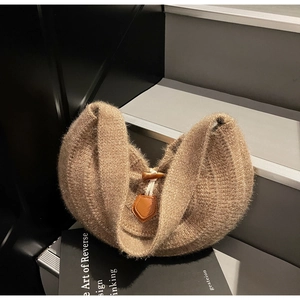 Détail de la texture en maille du sac avec fermeture à bouton corne et pièce en cuir marron