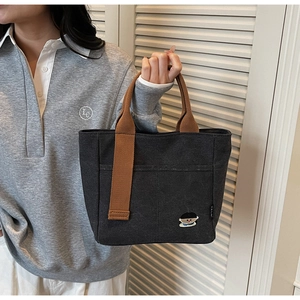 Detail of black canvas tote bag featuring brown straps and a cute cartoon boy embroidery