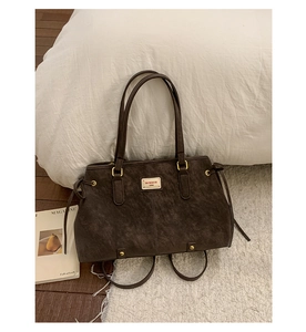 Close-up of dark brown tote bag with vintage texture and BAIMIAOER metal brand plate