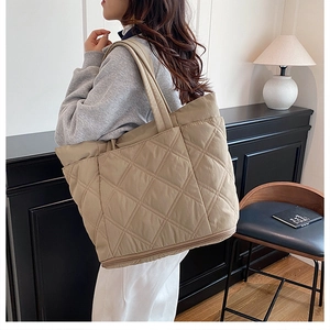 Detailed close-up of quilted khaki tote bag showing expandable zipper base and texture