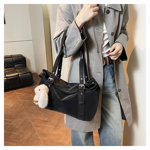 Detail of matte black leather tote bag featuring a white plush rabbit charm on a silver buckle