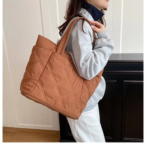 Side view of a large brown quilted tote bag showing its capacity on a model's shoulder