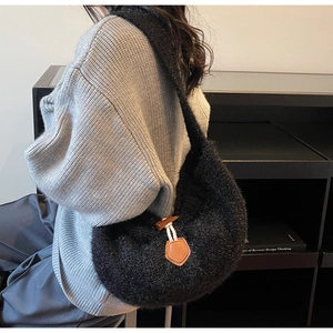 Détail du sac hobo noir pelucheux montrant la texture douce et le fermoir en corne