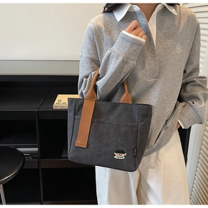 Détail du sac cabas en toile grise avec broderie cartoon et anses marron