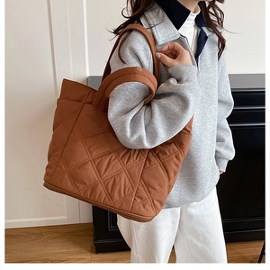 Brown quilted tote bag shown in a lifestyle setting, worn as a spacious shoulder bag