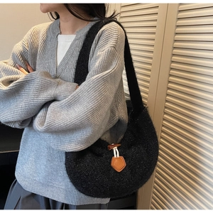 Gros plan d'un sac à bandoulière noir en peluche avec boucle en corne et détails tissés