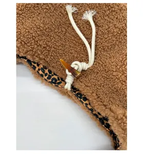 Detail of plush brown coat with horn button closure and leopard print lining