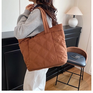 Close-up of brown quilted puffer tote bag with diamond pattern and padded shoulder strap