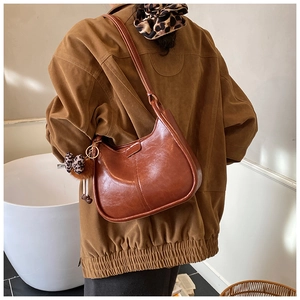 Braune Leder-Eimertasche mit Leoparden-Anhaenger an Model in der Rueckenansicht
