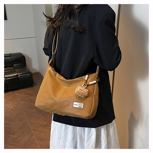Brown large capacity tote bag with bear charm detail and fashion patch shown on shoulder