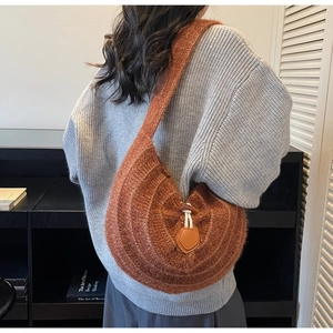 Detail of a brown knit crescent bag featuring a vintage wooden horn buckle and white rope