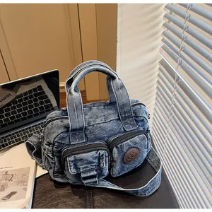 Detail of blue denim crossbody bag with multiple zip pockets and adjustable strap