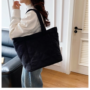Quilted tote bag detail on a person showing the large capacity and lightweight nylon texture