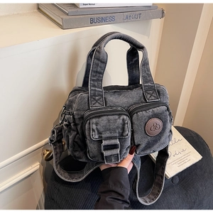 Close-up of black washed denim crossbody bag featuring utility pockets and metal buckle