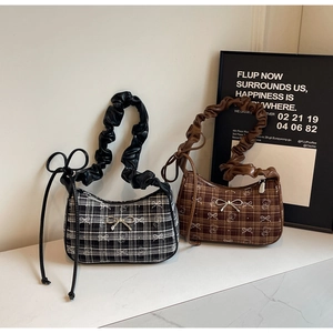 Detail of plaid pleated hobo bags with metallic bows and bear print on marble surface