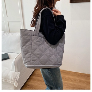 Close-up of grey quilted tote bag featuring elegant diamond lattice stitching and handles