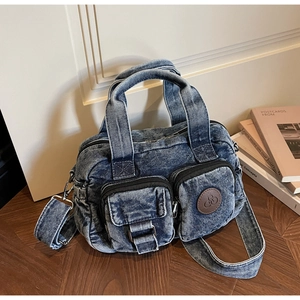 Detail of vintage denim crossbody bag with functional front pockets and leather logo tag