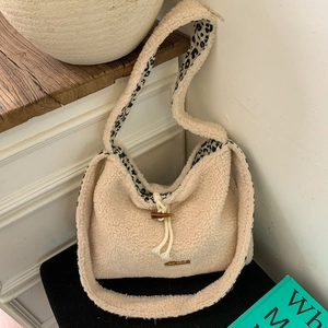 Close-up of fluffy white faux fur tote bag featuring leopard print lining and horn button