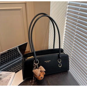 Detalle del bolso retro negro con logotipo dorado y amuleto de osito de peluche suave