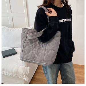 Detail of grey quilted tote bag with side pocket shown in cozy indoor lifestyle setting