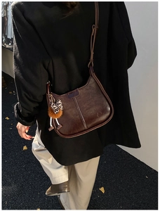 Detail der dunkelbraunen Leder-Eimertasche mit Leoparden-Pelzball-Anhänger am Schultergurt