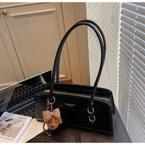 Detalle de bolso de hombro en PU negro con logo dorado y colgante de oso de peluche