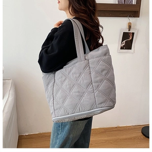 Macro detail of grey quilted tote bag showing diamond stitching and expandable zipper base