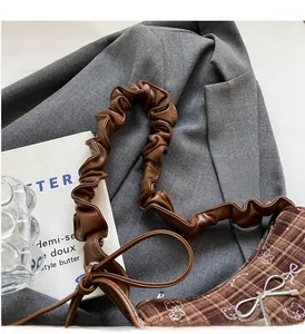 Close-up of brown plaid handbag with teddy bear pattern and pleated bow handle details