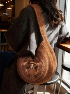 Sac à bandoulière en tricot marron avec fermoir bascule dans un café chaleureux