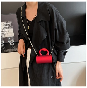 Détail d'un mini sac cylindrique rouge en acrylique avec bandoulière chaîne dorée