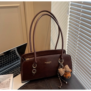 Detalle del bolso vintage marrón oscuro con logo dorado y colgante de osito mono