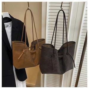 Detail of minimalist tote bags in brown and dark grey suede texture with drawstring knots