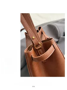 Detail of brown leather bucket bag showing gold rivets and high-quality stitching