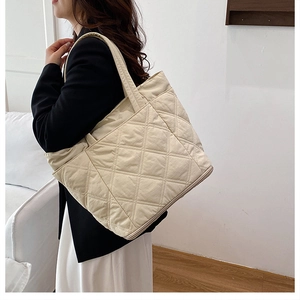 Detail of a large cream quilted tote bag with diamond pattern for daily commuting