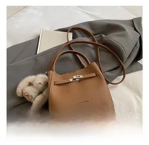 Brown litchi grain leather bucket bag with a plush bear charm and metallic buckle closure