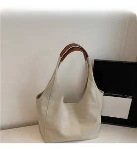 Close-up of a minimalist canvas tote bag featuring premium brown leather handles