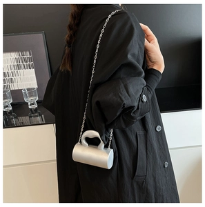 Détail d'un sac à main cylindrique argenté avec bandoulière en chaîne et poignée chic